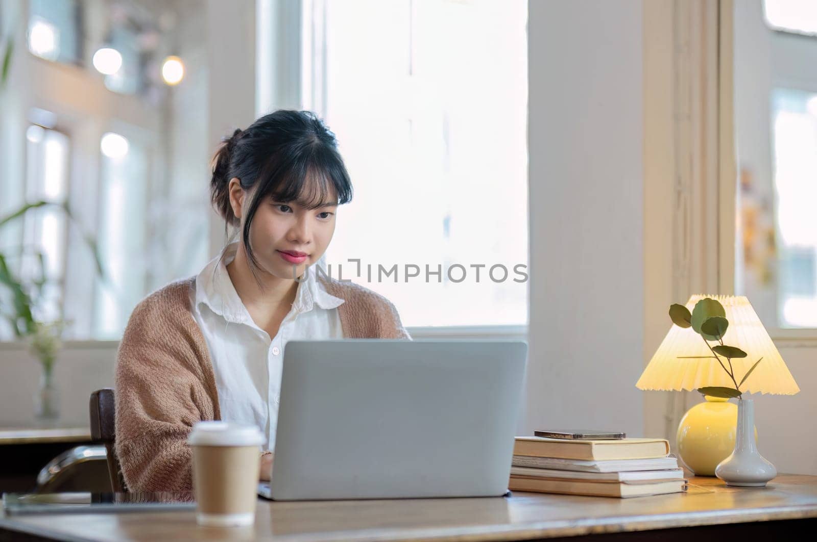 Asian female student studying online, studying on a video call, zoom call, passionate Asian female teacher learning English online with a laptop computer by wichayada