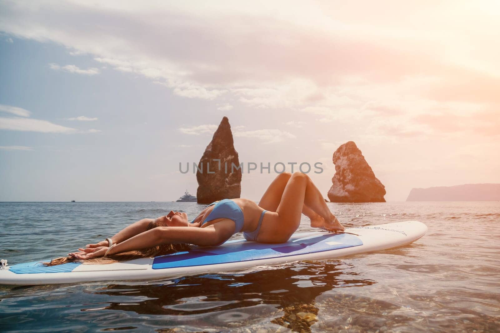 Woman sea sup. Close up portrait of happy young caucasian woman with long hair looking at camera and smiling. Cute woman portrait in bikini posing on sup board in the sea by panophotograph