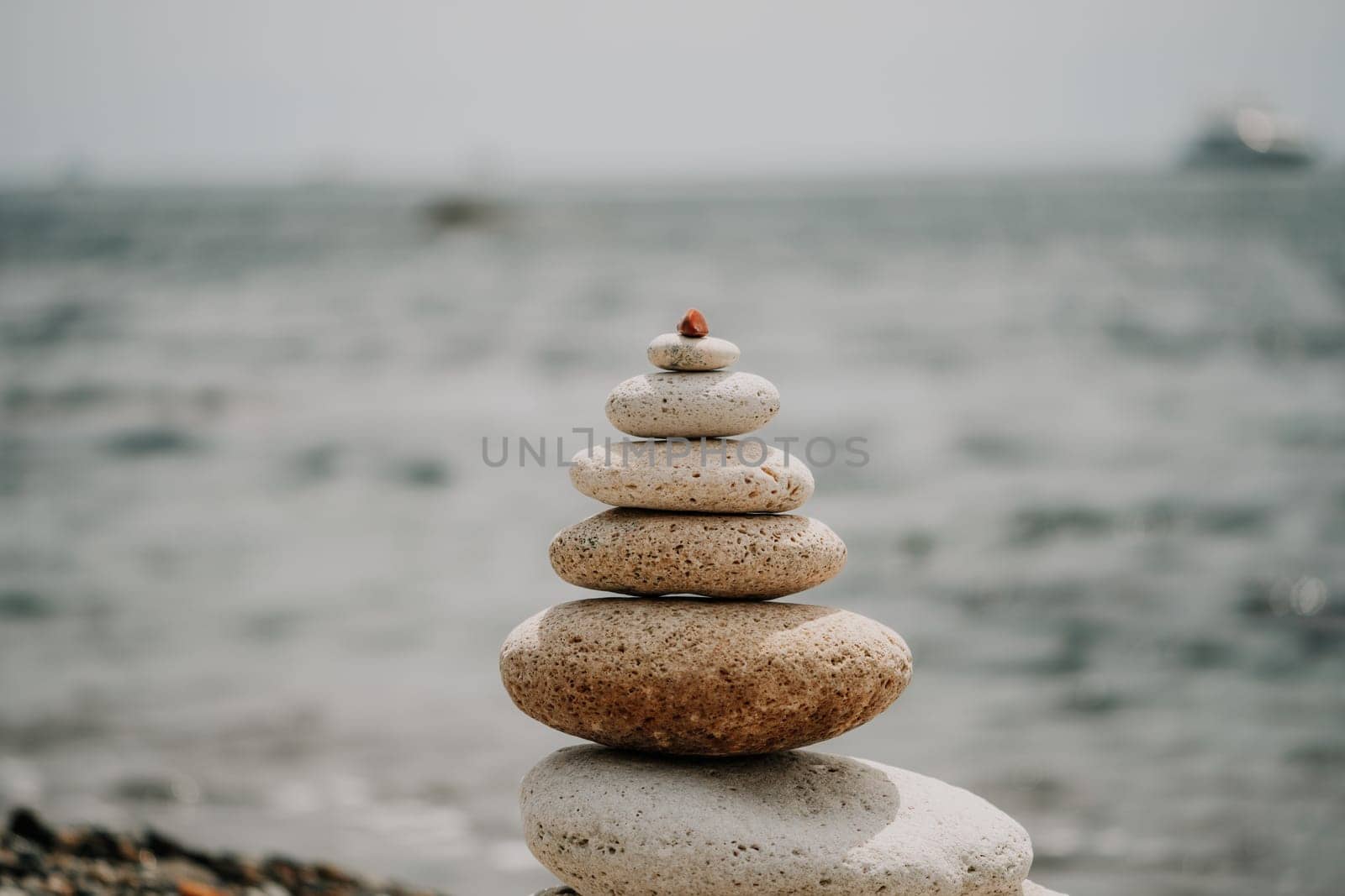 Pyramid stones on the seashore with warm sunset on the sea background. Happy holidays. Pebble beach, calm sea, travel destination. Concept of happy vacation on the sea, meditation, spa, calmness.