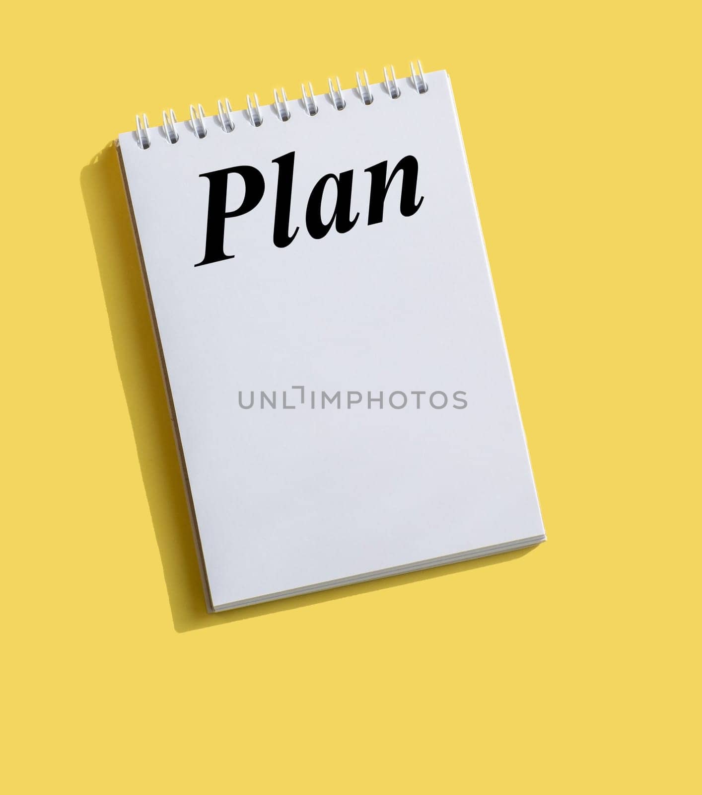 Inscription PLAN written on note paper on a bright yellow background. Concept in business. Plans for the new year. Resolutions, plan, goals, action, checklist, idea concept