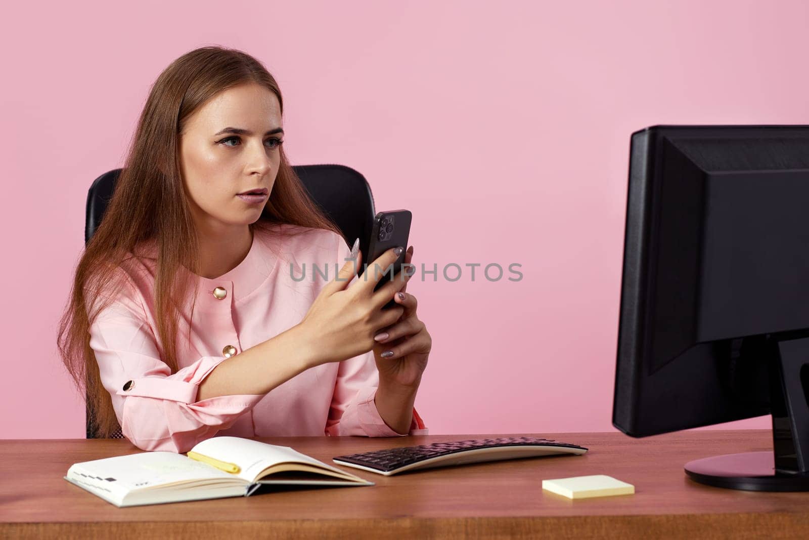 attractive young business woman using phone on pink background