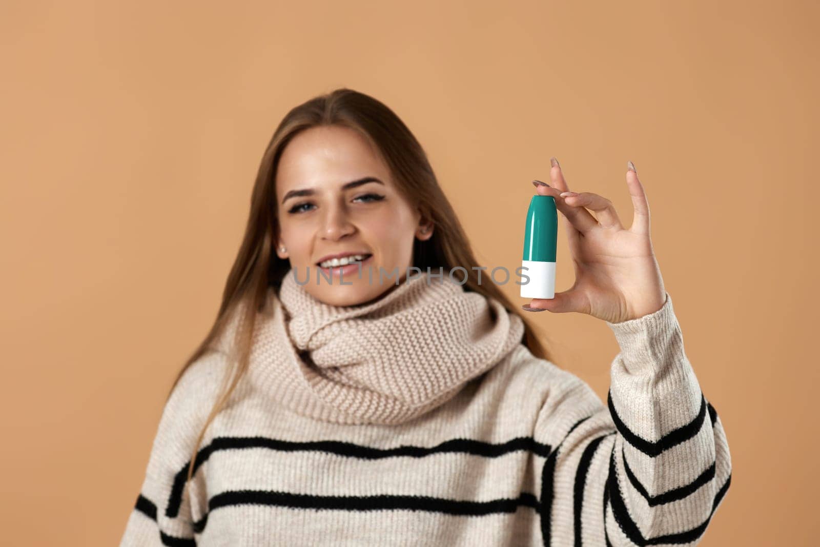 smiling caucasian woman holds nasal spray for allergies on beige background. Treatment of the disease