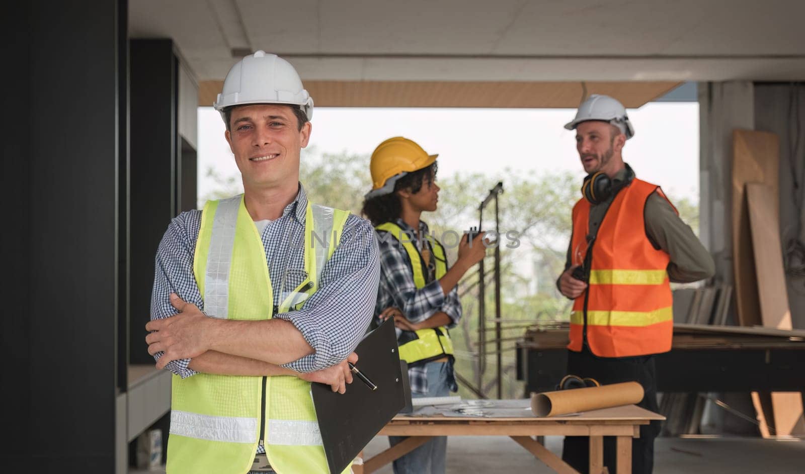 Portrait of an engineer standing and looking at the camera with a team of professional engineers meeting to plan a construction project. by wichayada