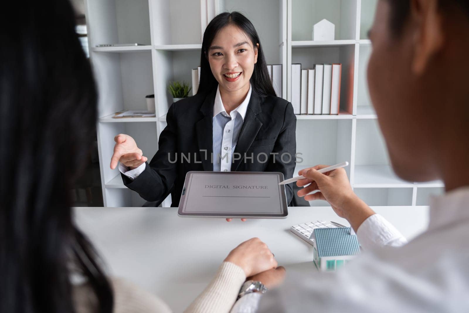 House plans with agents and couple clients Discuss the purchase contract, whether to get insurance or a real estate loan..