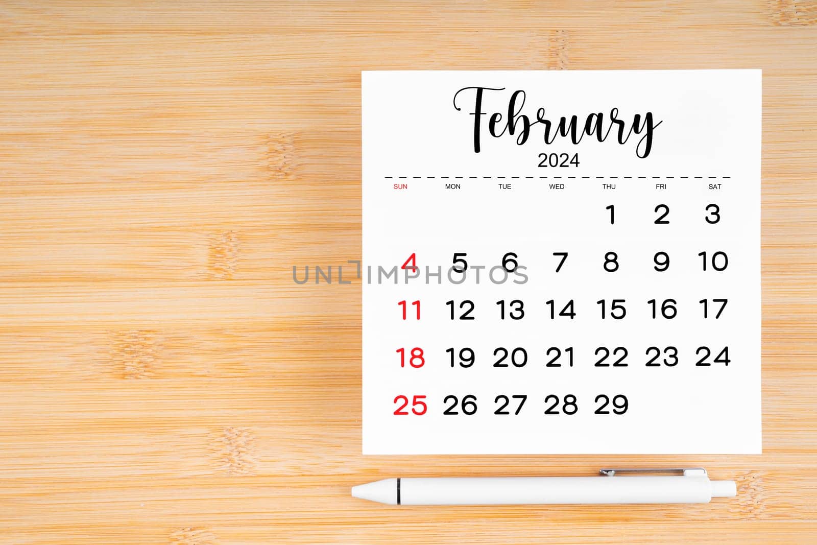 February 2024 calendar page and pen on wooden background. by Gamjai