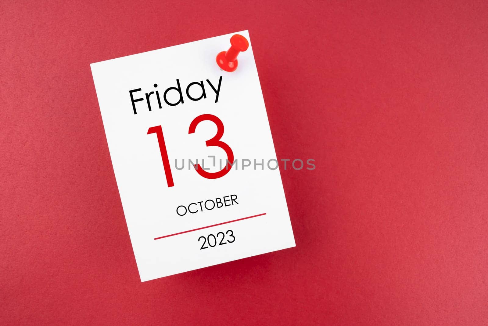 Calendar Friday the 13th October 2023 and push pin on red background.