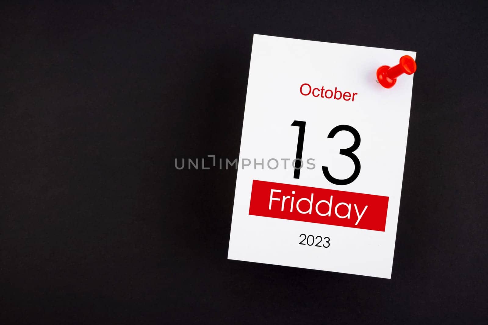 Calendar Friday the 13th October 2023 and push pin on black. by Gamjai