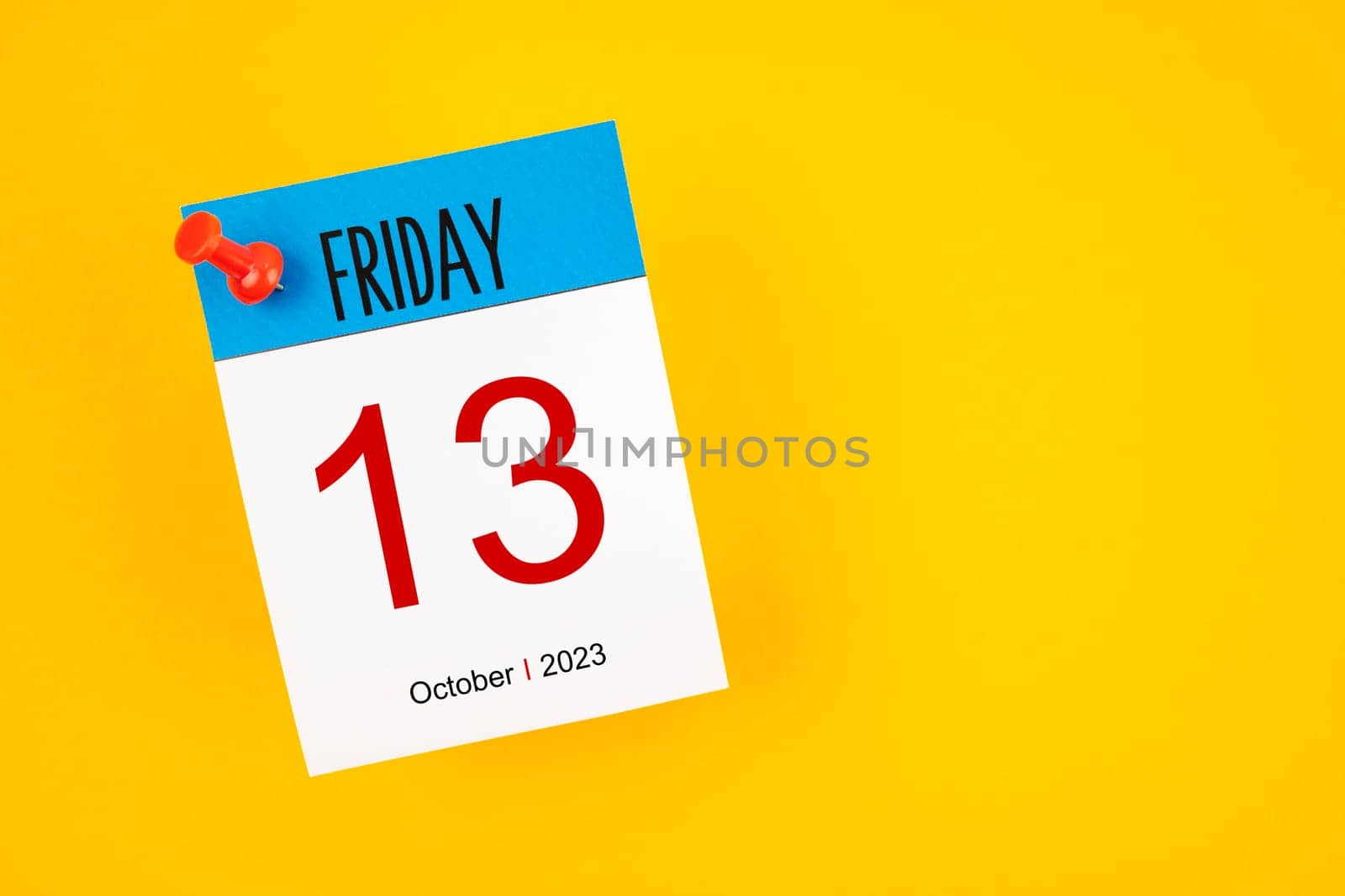 Calendar Friday the 13th October 2023 and push pin on yellow background.