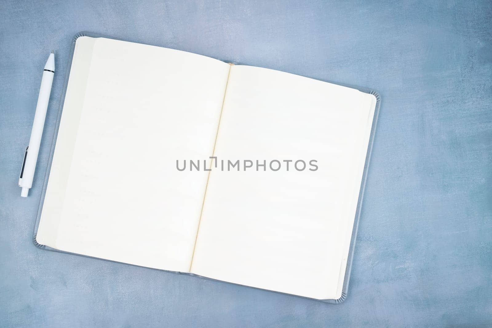 The Directly above shot of open blank book on table with pen. by Gamjai