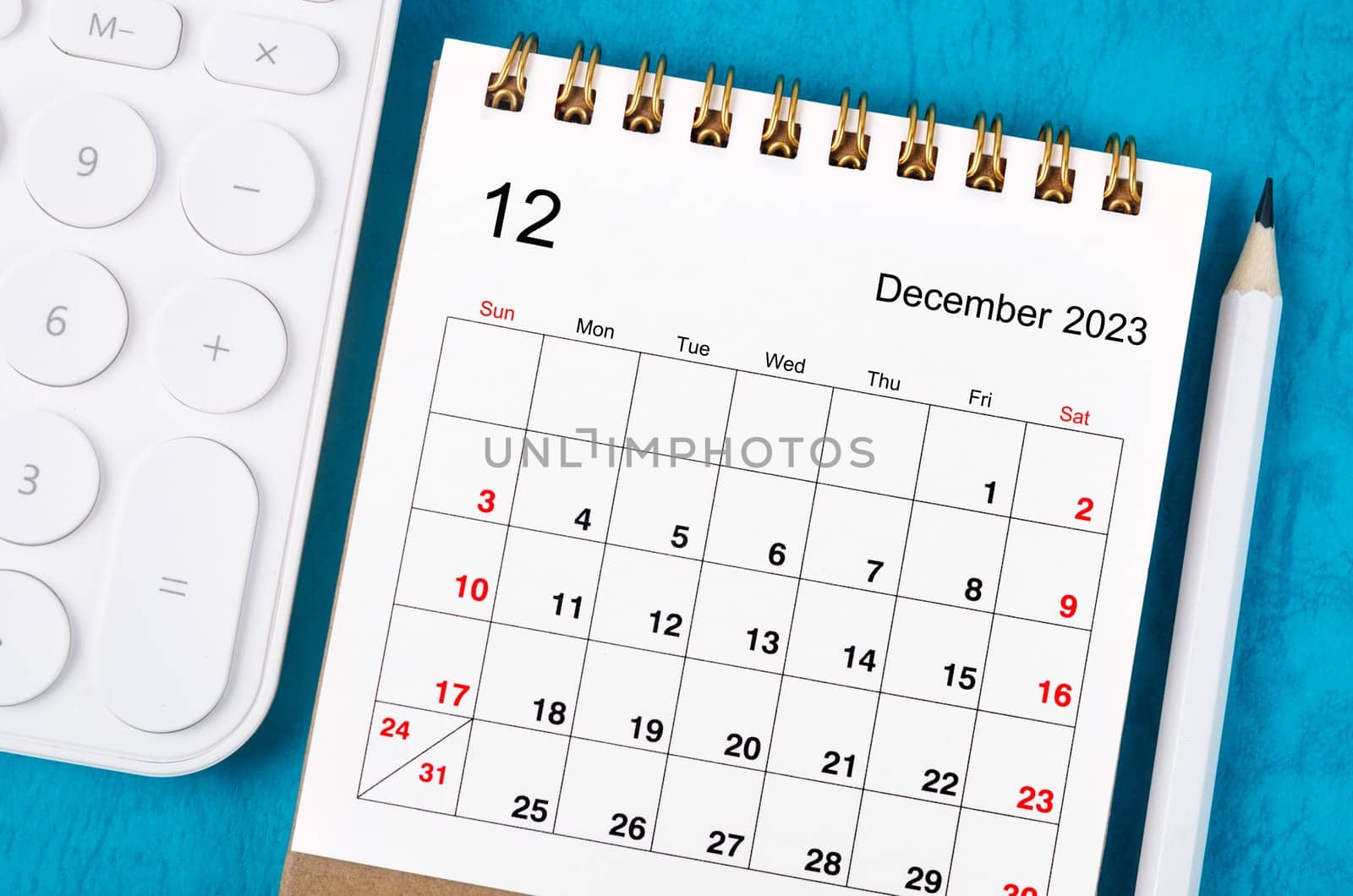 Close up the December 2023 Monthly desk calendar for 2023 year with calculator and wooden pencil. by Gamjai