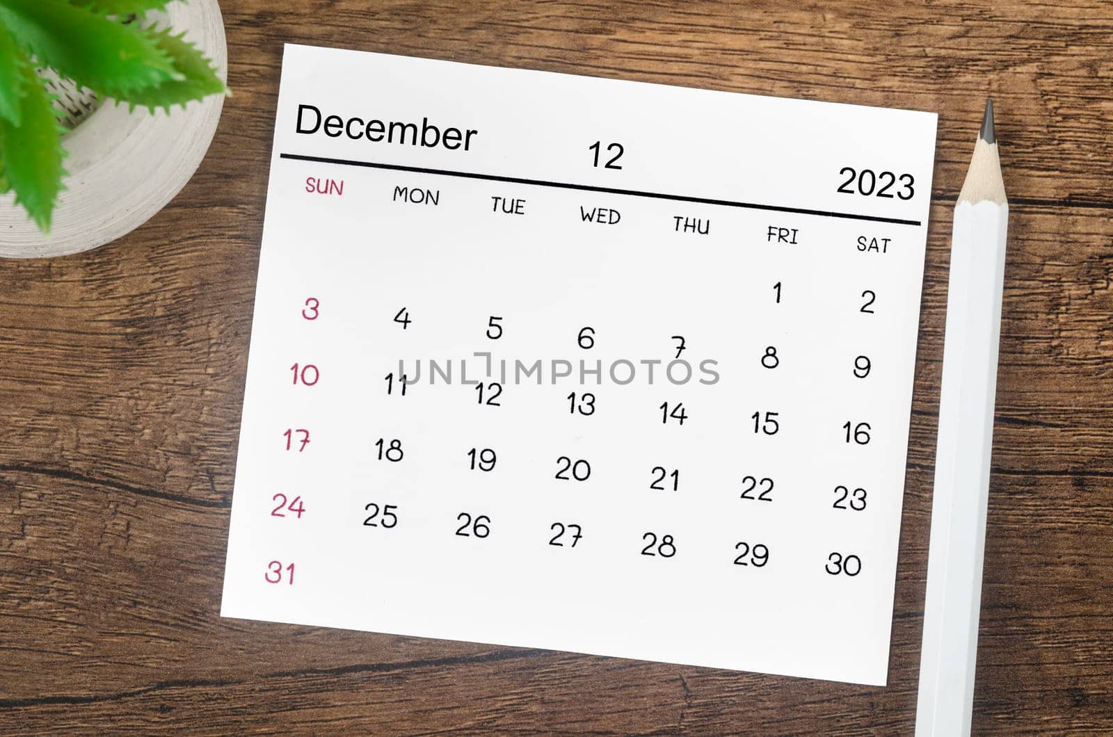 The December 2023 Monthly calendar for 2023 year with pen on wooden background. by Gamjai