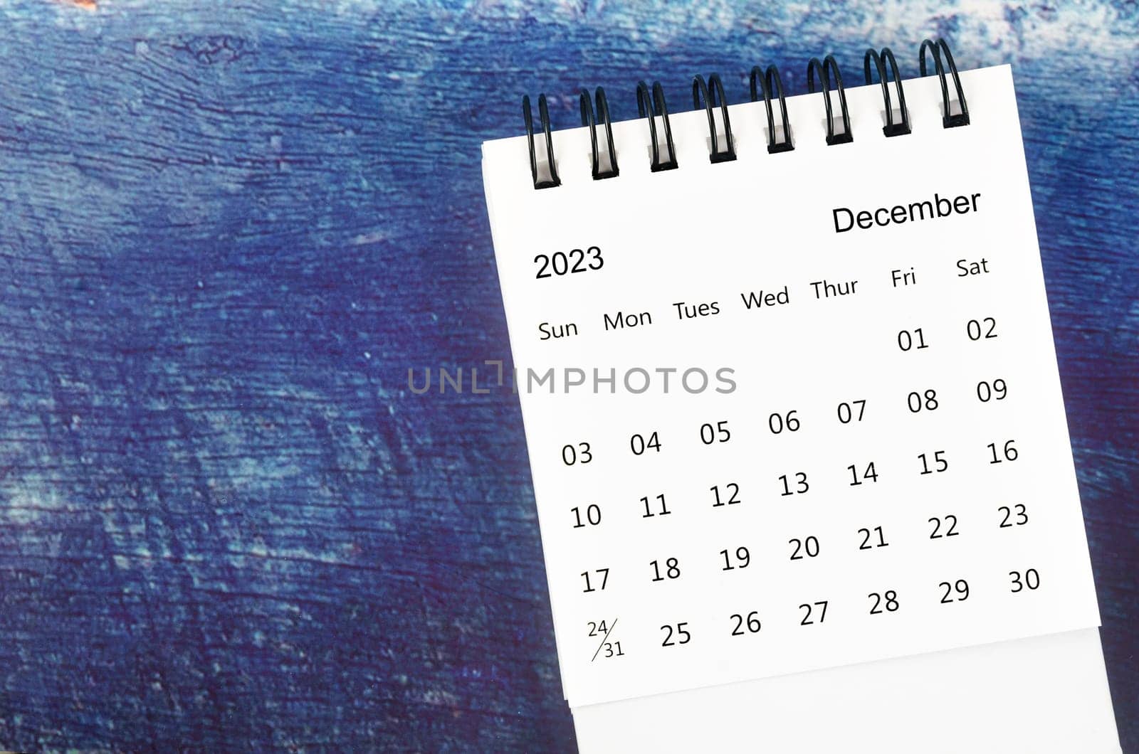 The December 2023 Monthly desk calendar for 2023 year on old blue wooden background. by Gamjai