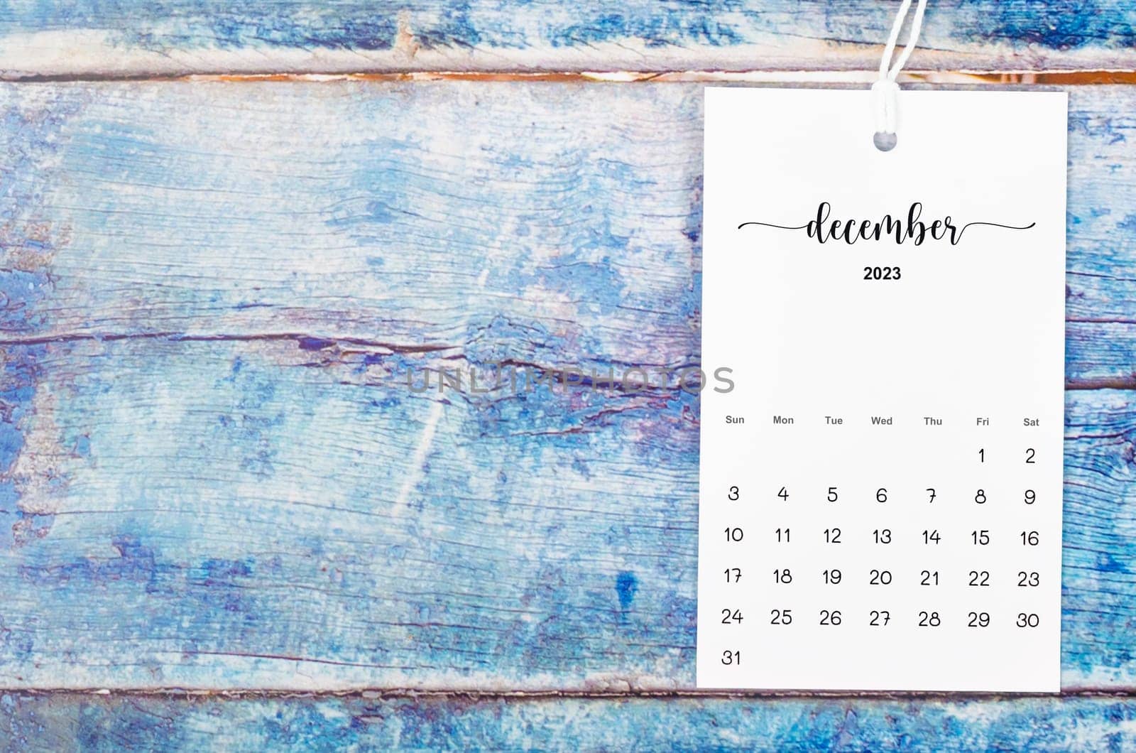 The December 2023 calendar page hanged with white rope  on old blue wooden background. by Gamjai