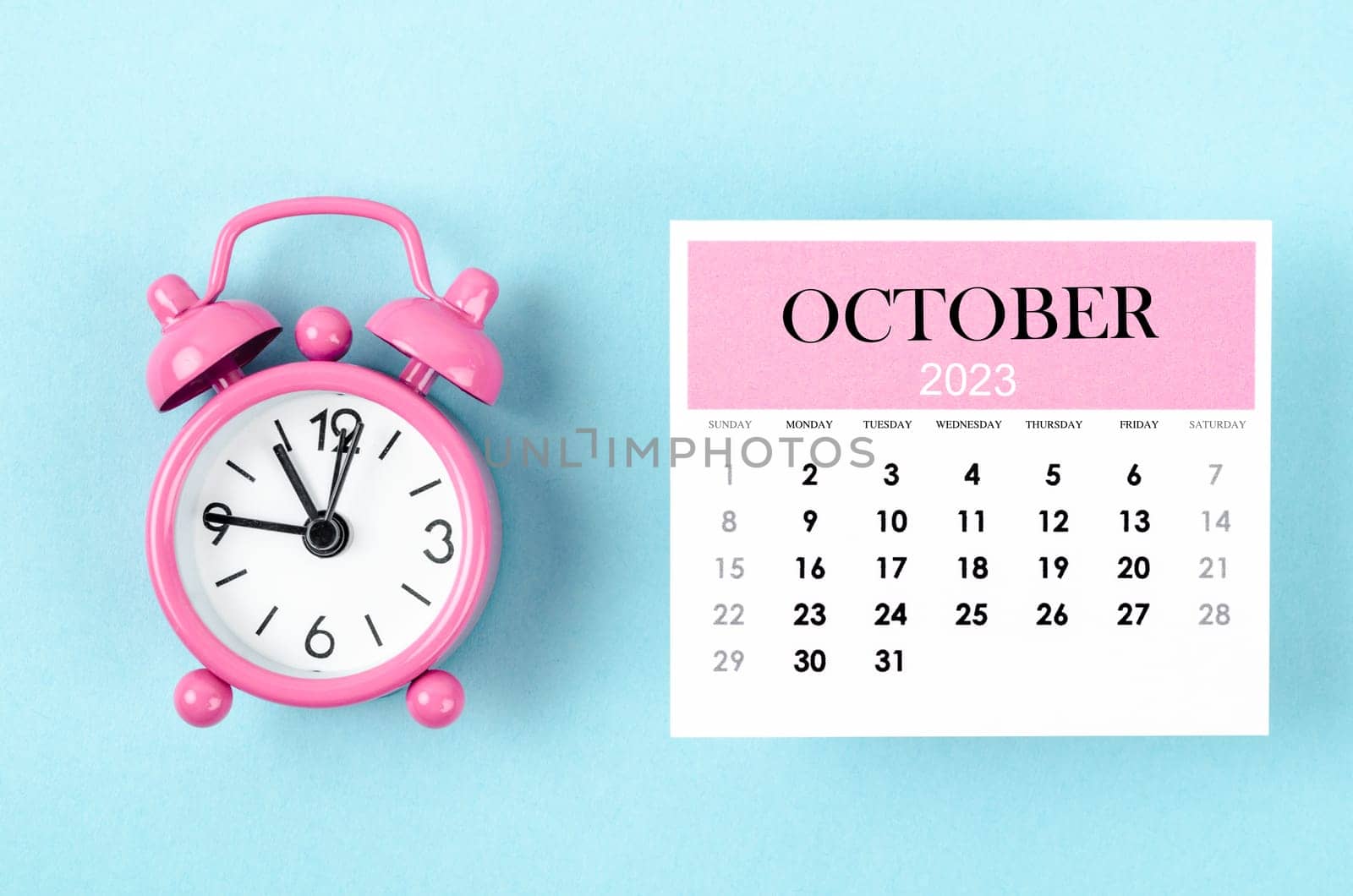 October 2023 Monthly calendar for 2023 year with pink color alarm clock on blue background.