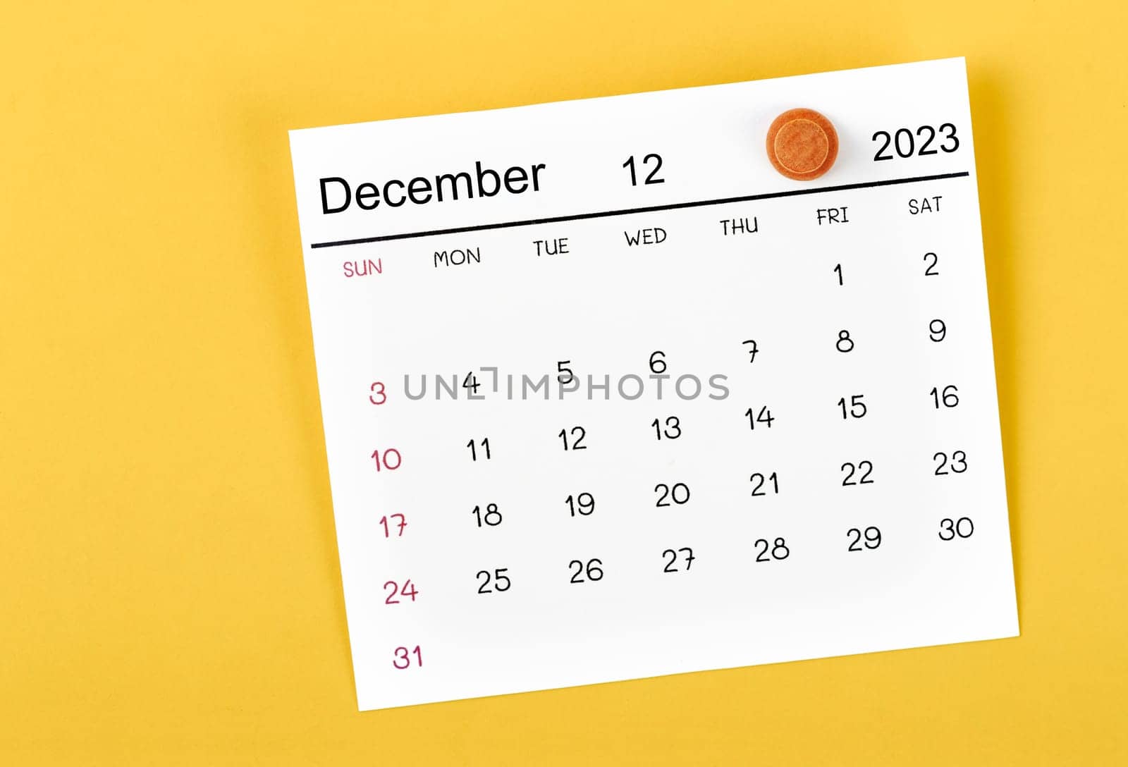 The December 2023 and wooden push pin on yellow background. by Gamjai