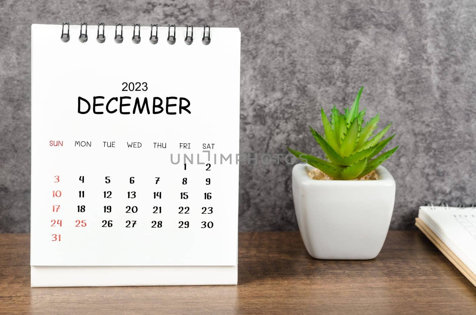 The December 2023 Monthly desk calendar for 2023 with diary on wooden table. by Gamjai