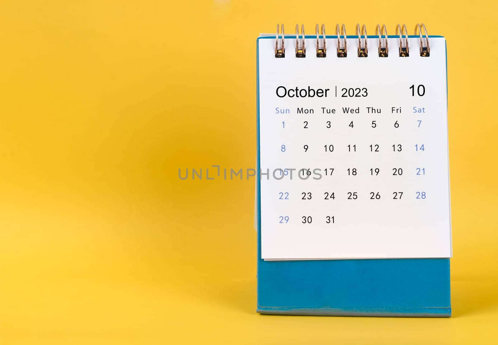 The October 2023 desk calendar on yellow color background. by Gamjai