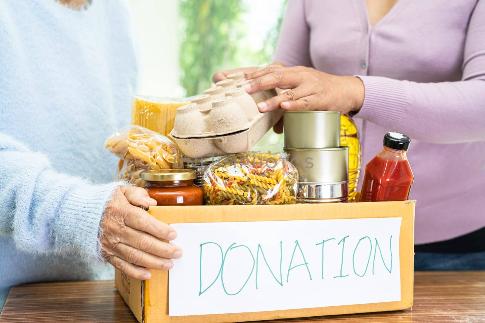 Volunteers putting various dry food in donation box for help people.