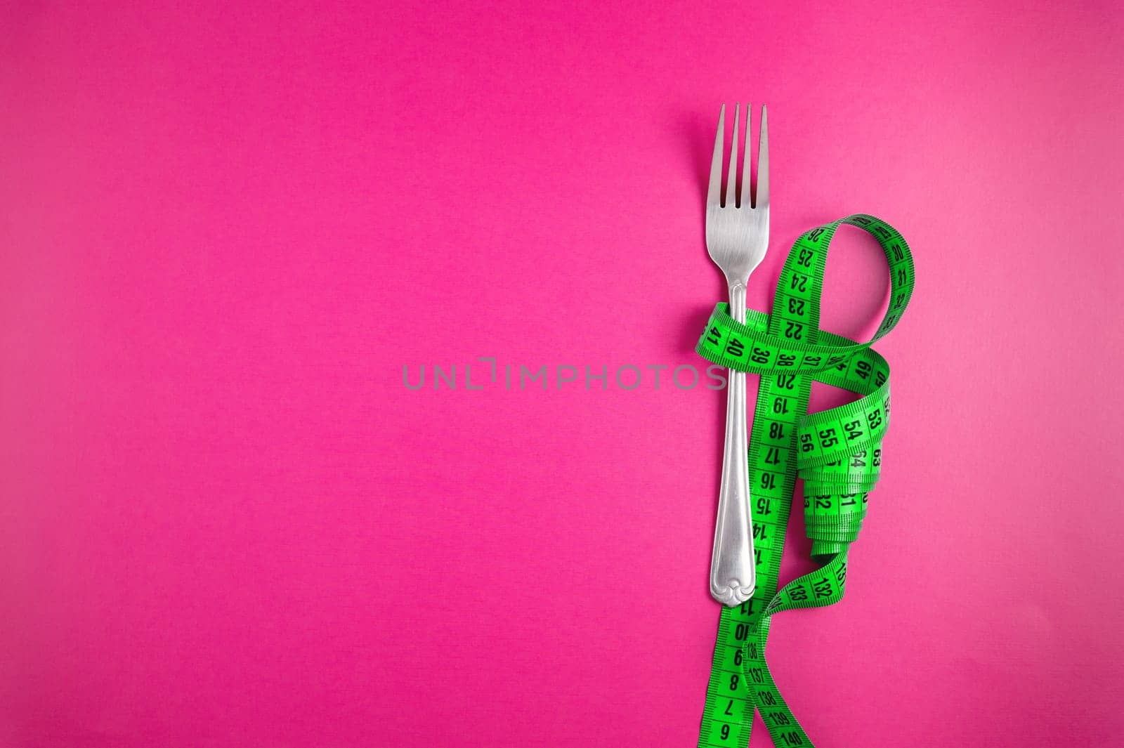 Green tape measure with cutlery on a colored background, top view. Diet and fasting. Weight loss by yanik88