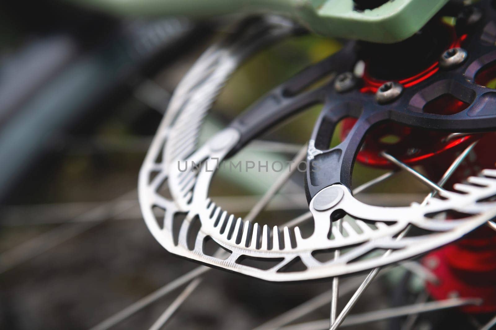 Close-up of Hydraulic bicycle disc brakes, gray metal disc attached to a bicycle wheel close-up, effective popular mountain bike brakes. Bicycle spokes on a gray background.
