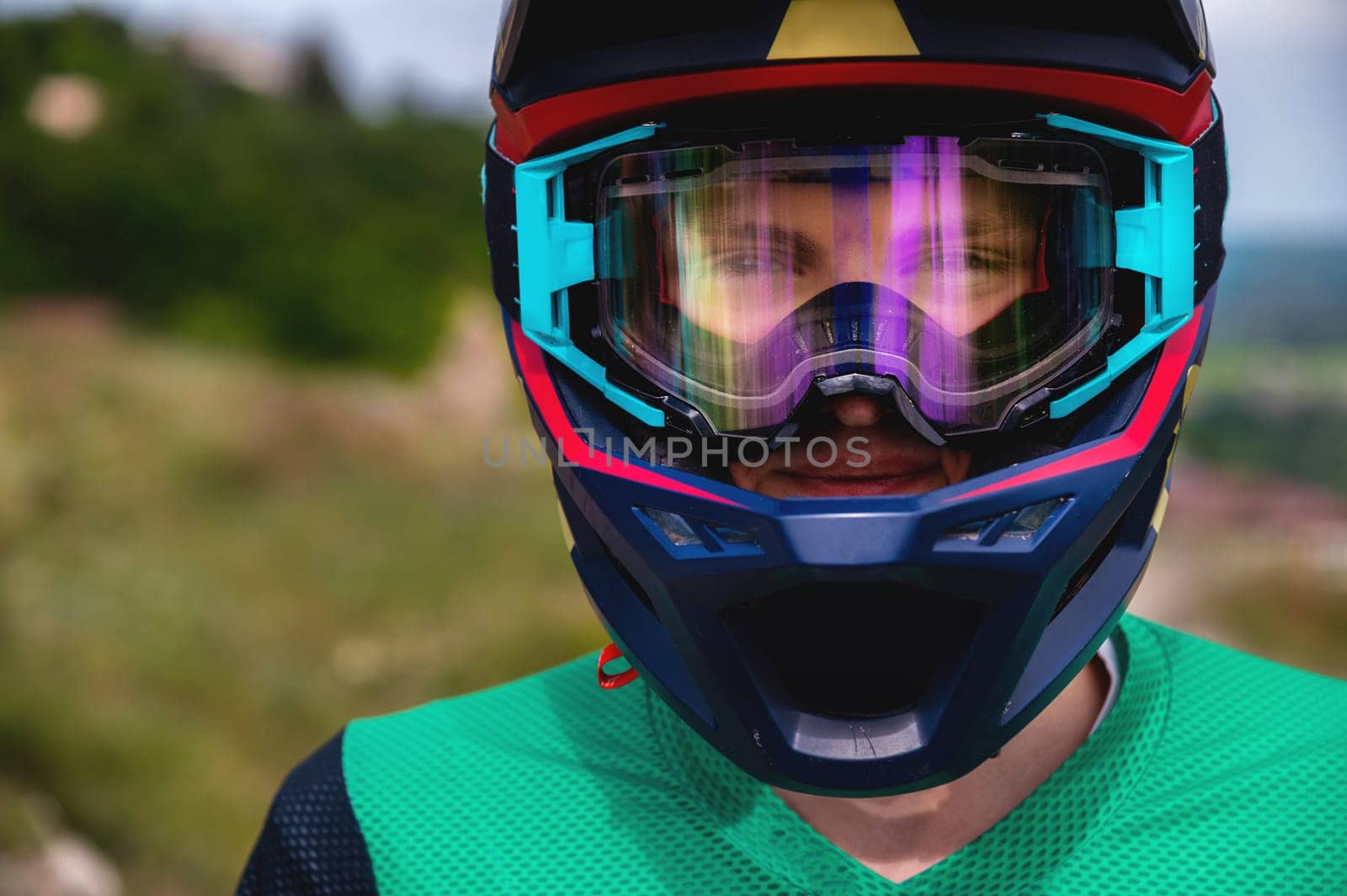 Close-up portrait of a MTB and downhill racer on a mountain trail. Colored full helmet, clear glasses and smiling guy by yanik88