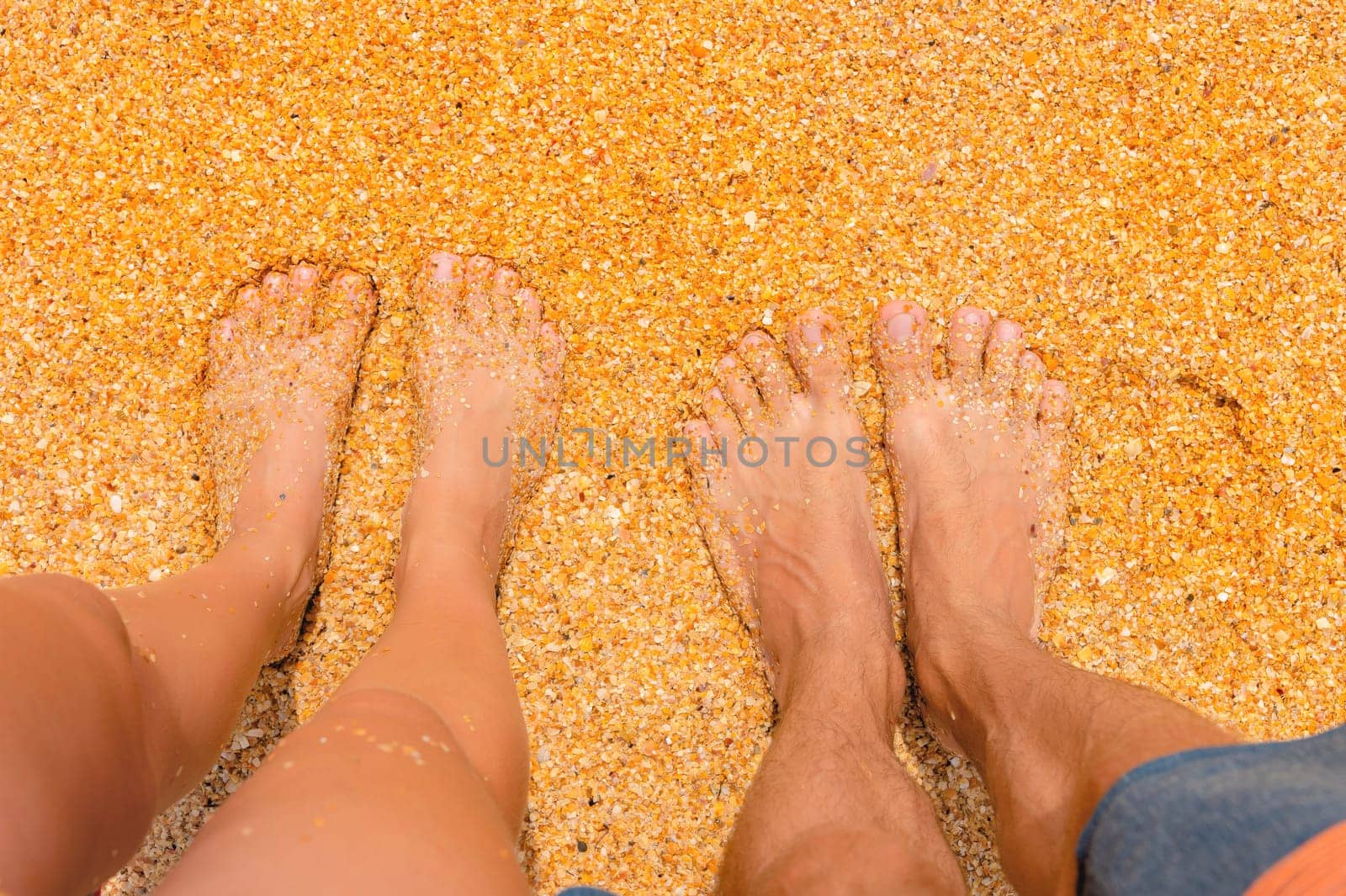 Top view from a couple standing on the sand, romantic. Love story. Female and male legs stand side by side on the sandy beach first person view by yanik88