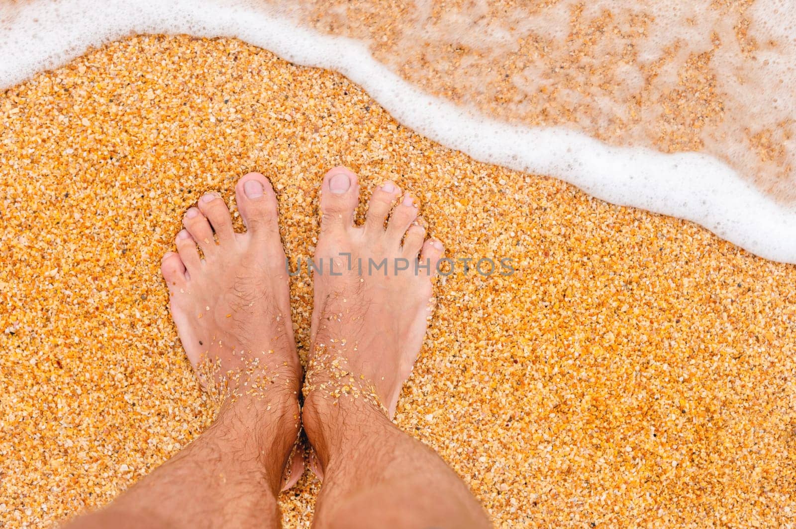 Relaxing on the ocean beach, feet on the sea sand. bare feet on a sandy beach with waves and foam by yanik88