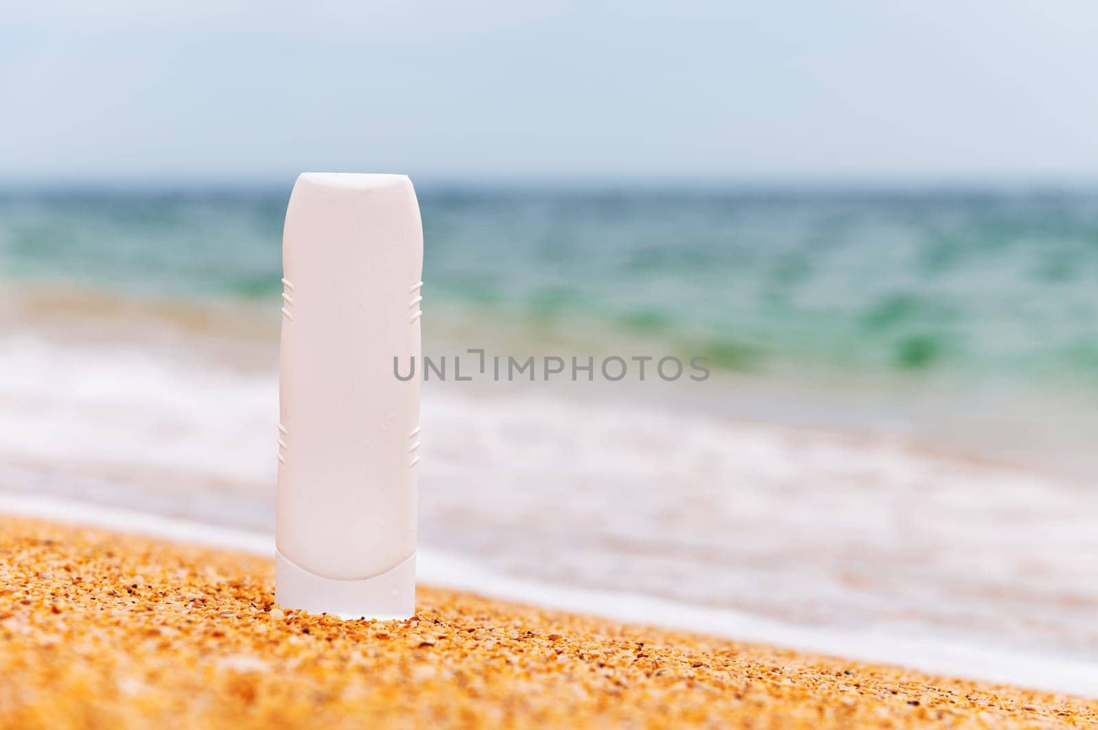 empty cosmetic skin care cream or sunscreen on sandy beach on sea background. White plastic tube with sunscreen. Before going out to sea or sunbathing, apply sunscreen to protect against ultraviolet rays. to prevent skin cancer.
