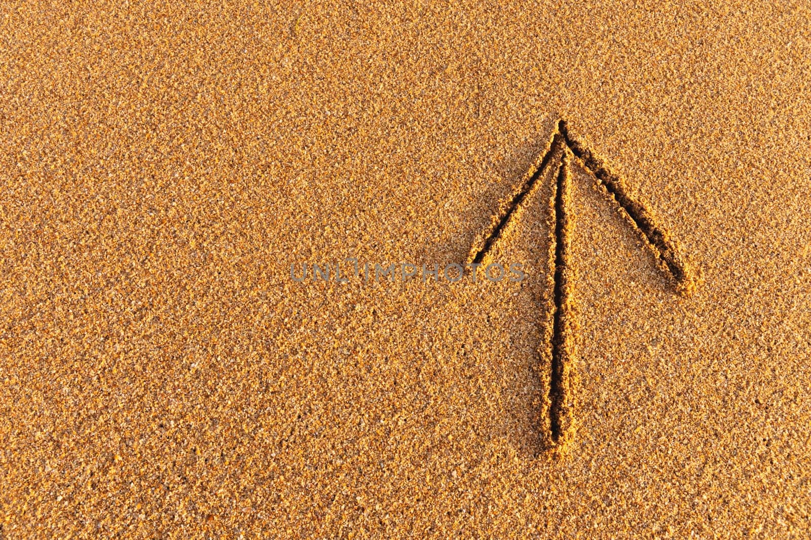 Drawn arrow on the sand. drawing of an arrow sign pointing up, path direction.