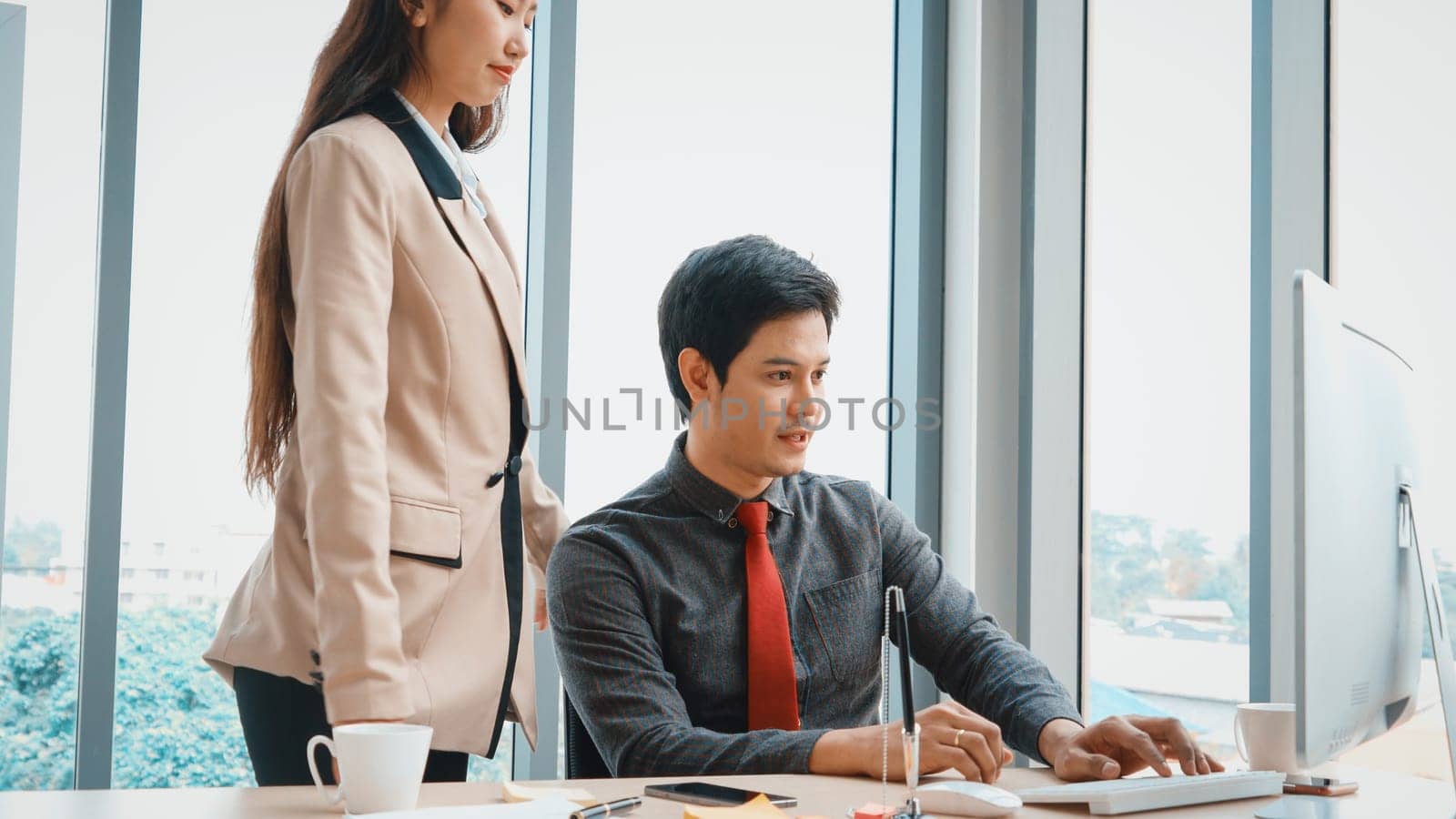 Two business people talk project strategy at office meeting room. Businessman discuss project planning with colleague at modern workplace while having conversation and advice on financial report. Jivy