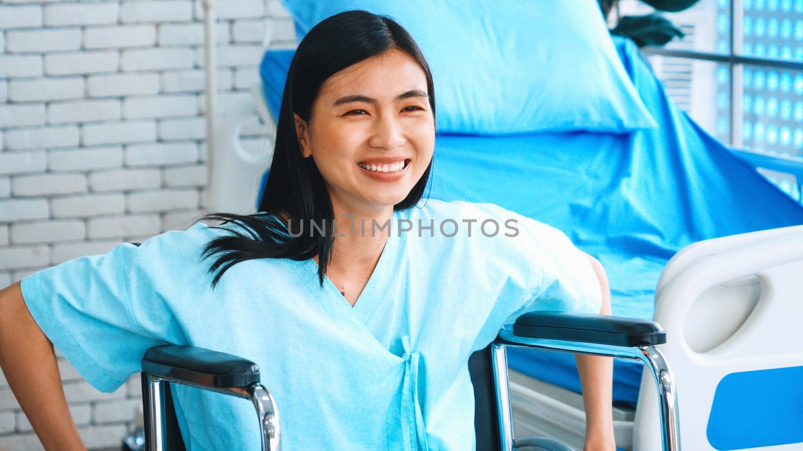 Young happy Asian woman on wheelchair in a hospital ward . Medical healthcare and patient treatment concept. Jivy