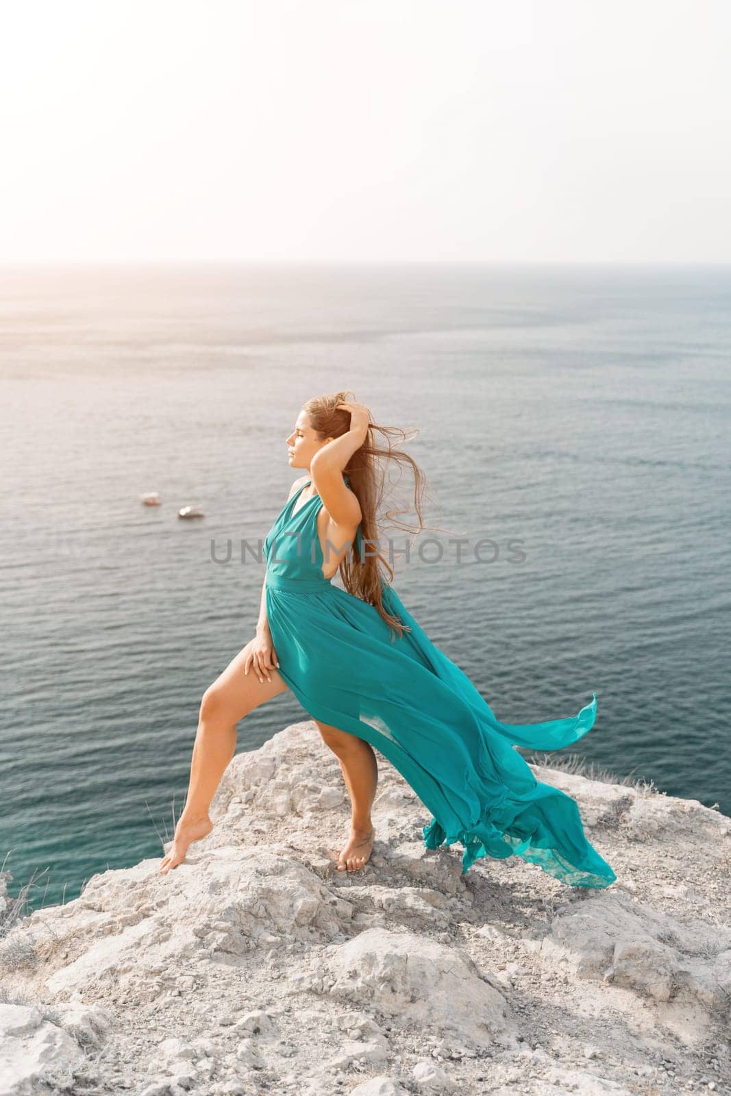 Woman sea trevel green dress. Side view a happy woman with long hair in a long mint dress posing on a beach with calm sea bokeh lights on sunny day. Girl on the nature on blue sky background