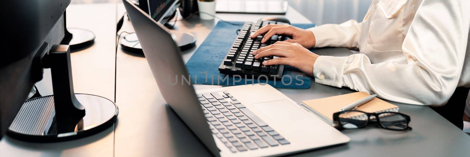 Office worker sitting on workspace desk, focused and engaged, using computer and typing on keyboard to input data ensure accurate data management in the modern workplace. Trailblazing