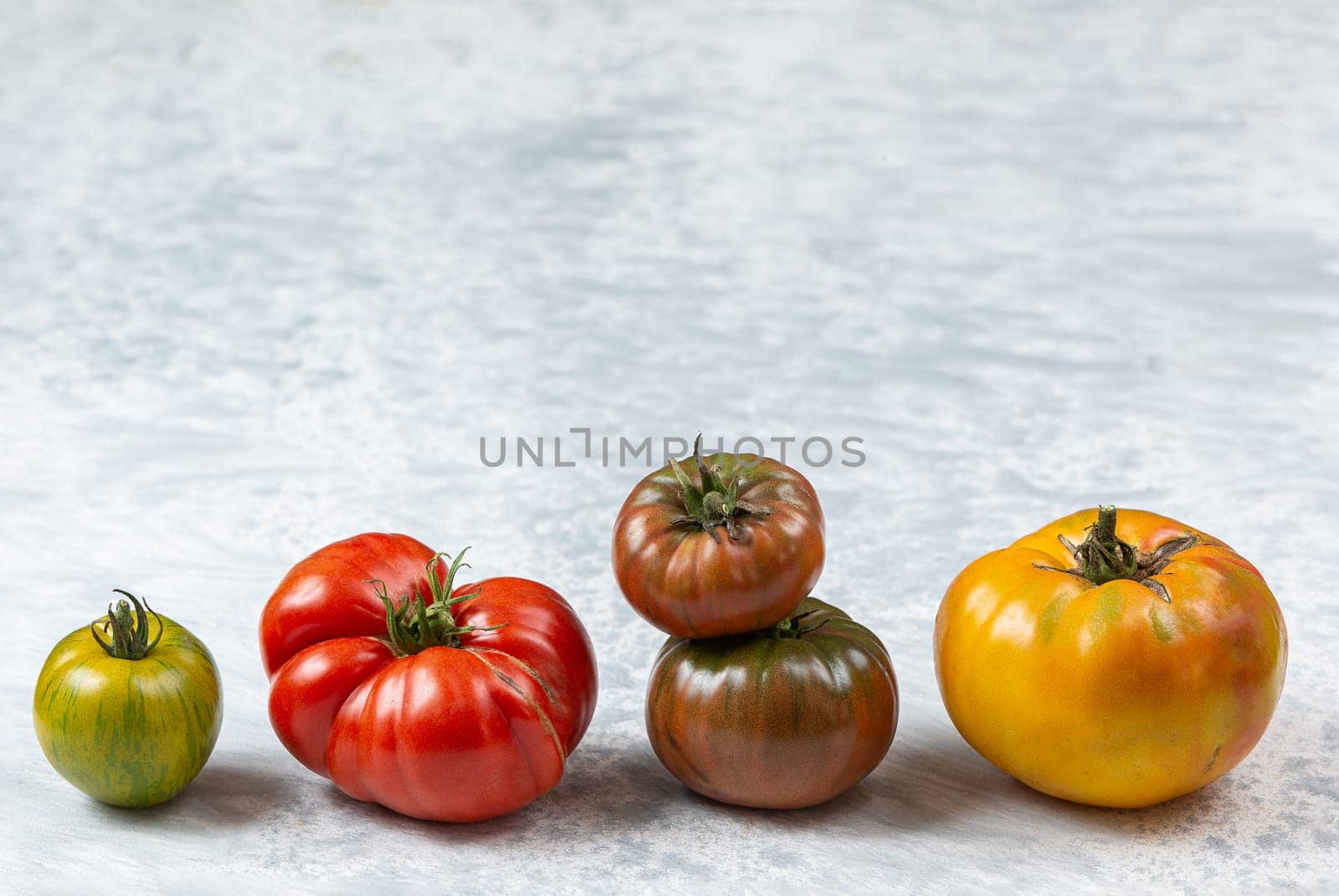 Line of freshly harvested heirloom and heritage tomatoes over marble background by JPC-PROD