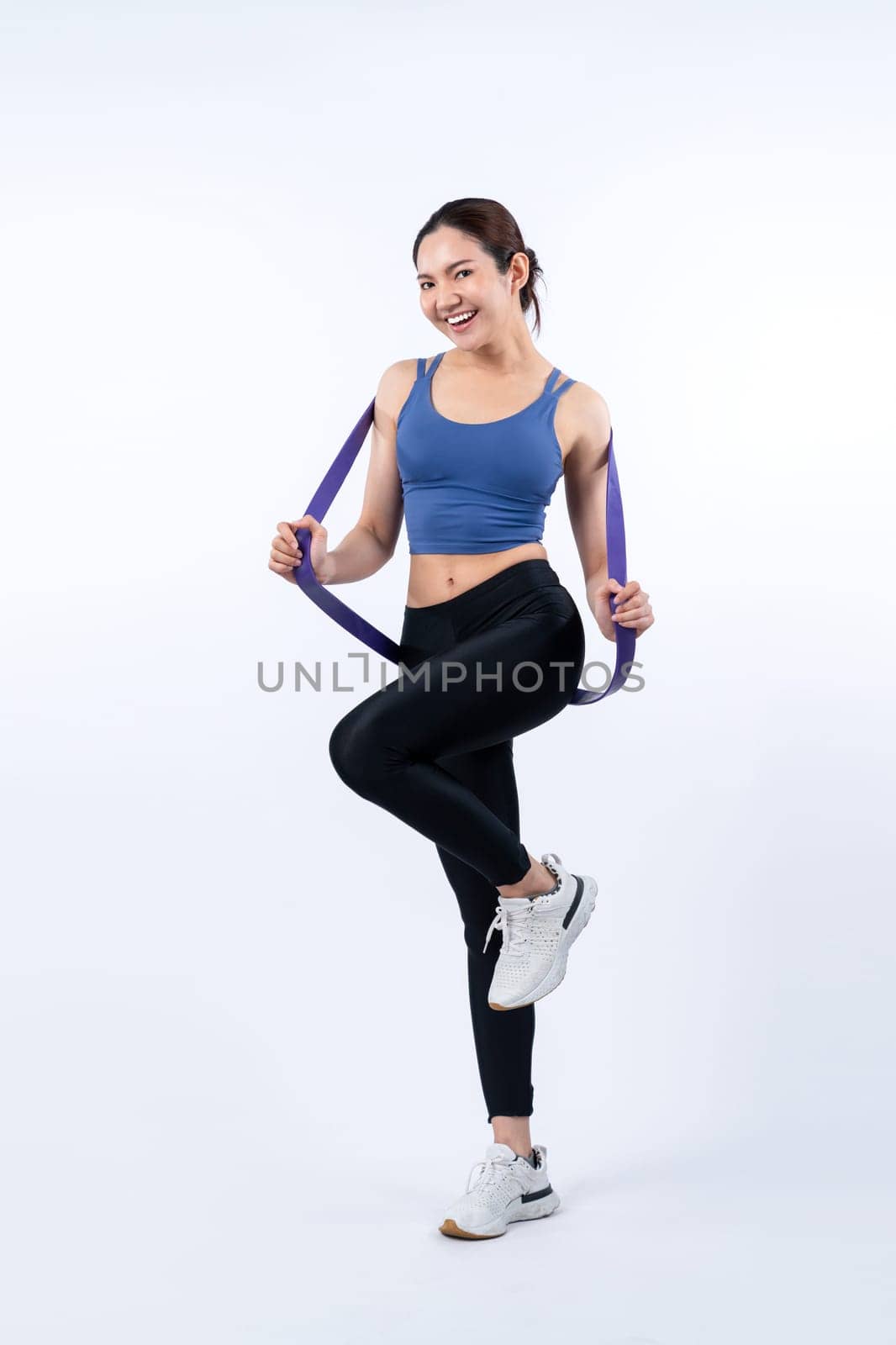 Vigorous energetic woman in sportswear portrait stretching resistance sport band. Young athletic asian woman strength and endurance training session workout routine concept on isolated background.