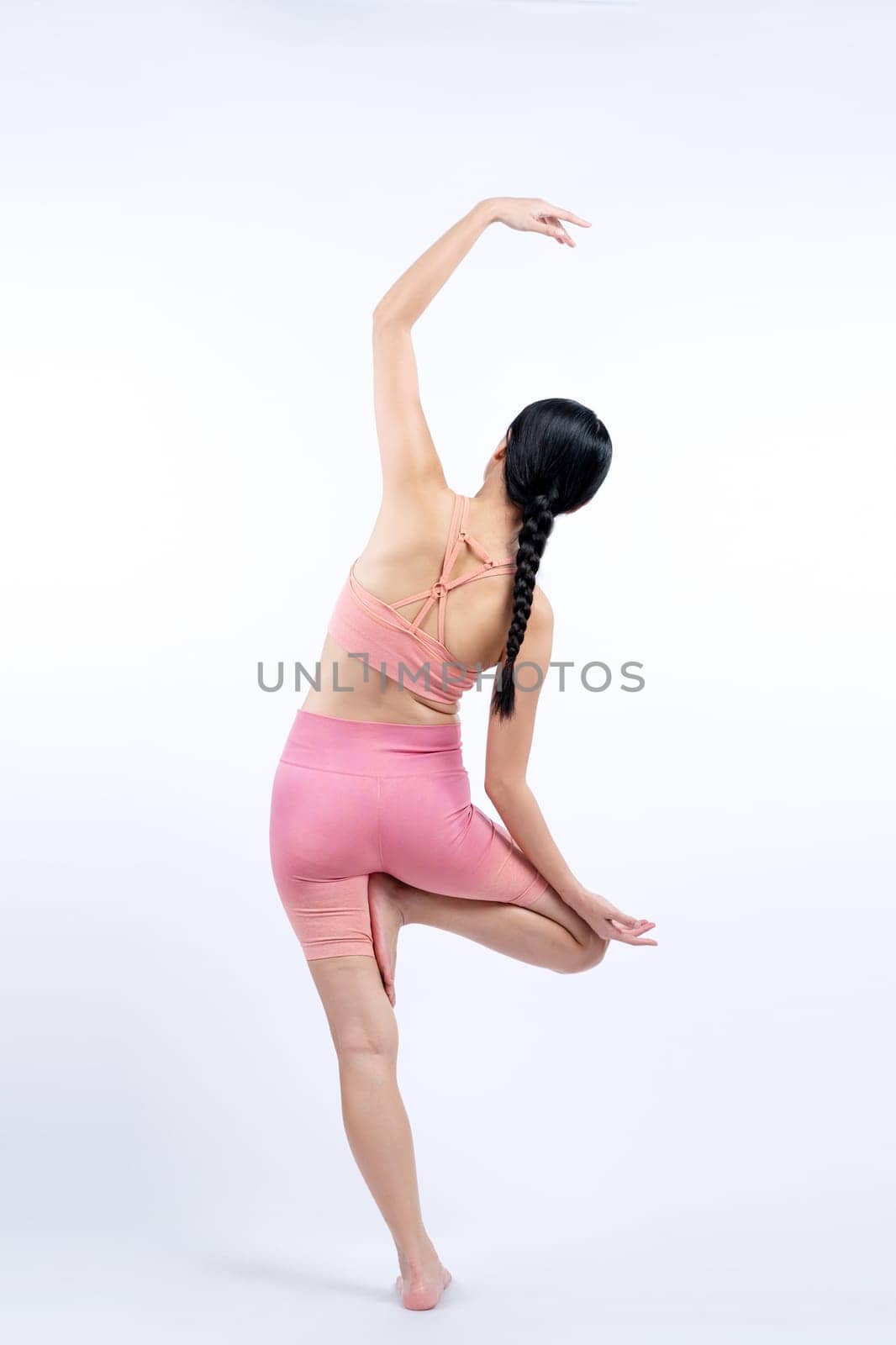 Asian woman in sportswear doing yoga exercise in standing pose on fitness as her workout training routine. Healthy body care and meditation yoga lifestyle in full shot on isolated background. Vigorous