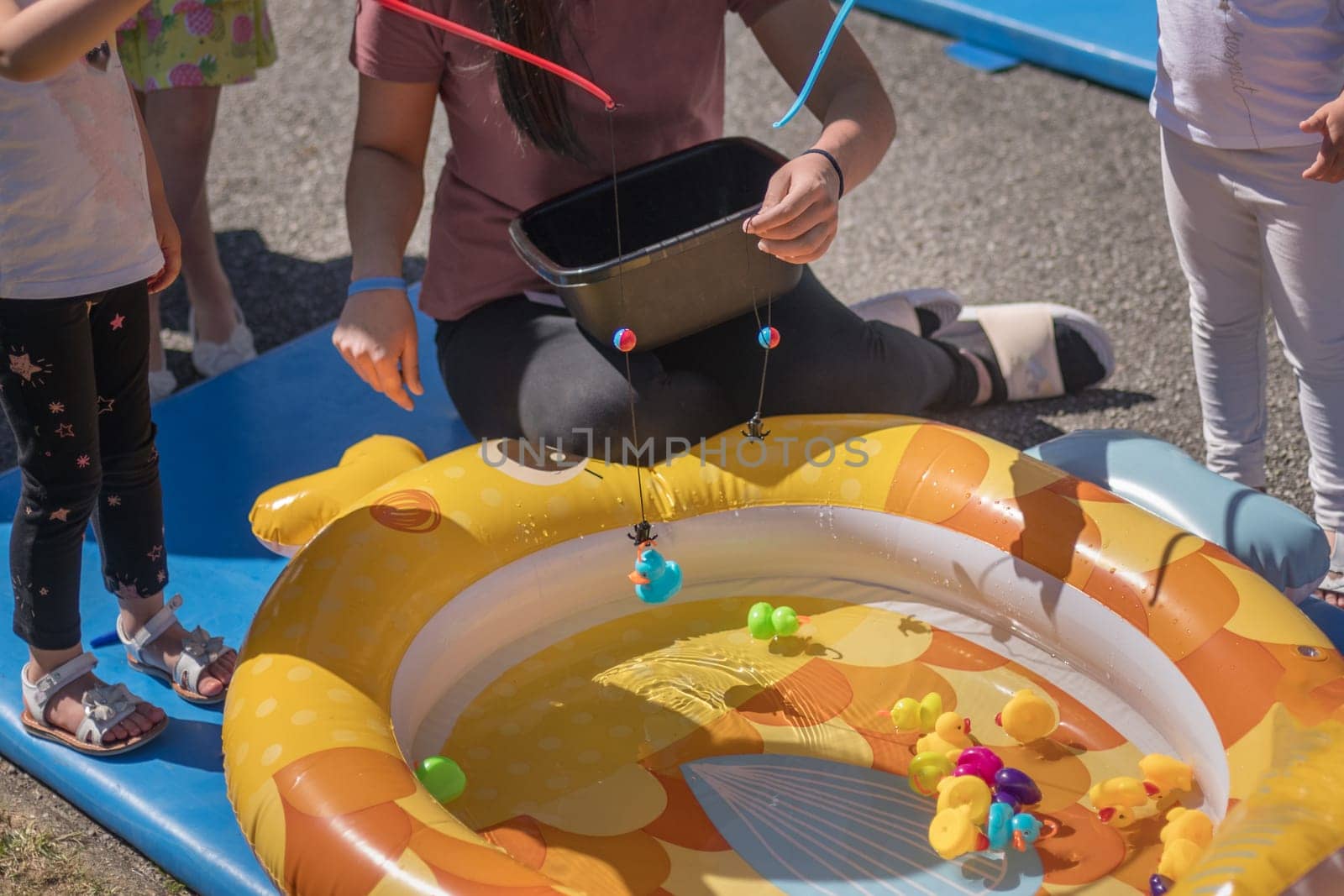 Girls catch rubber ducks with fishing rod in a park