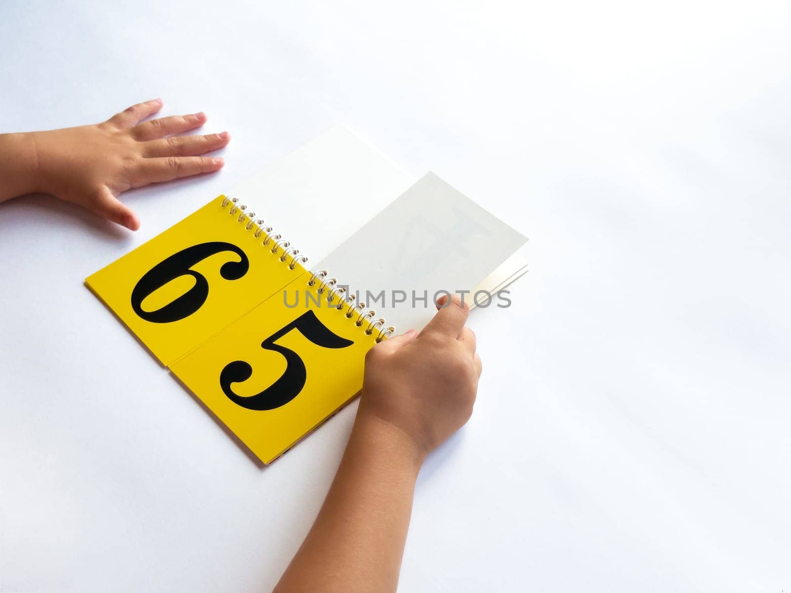 Child learning numbers with flashcards and hands on a white background.