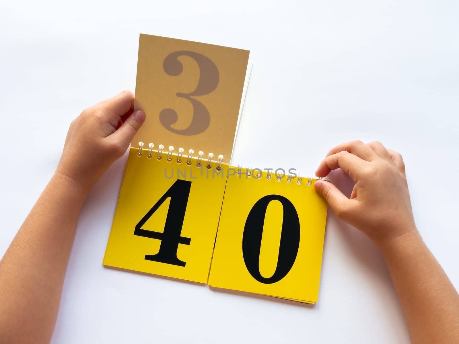 Childs hands flip through yellow pages with numbers on a white background.