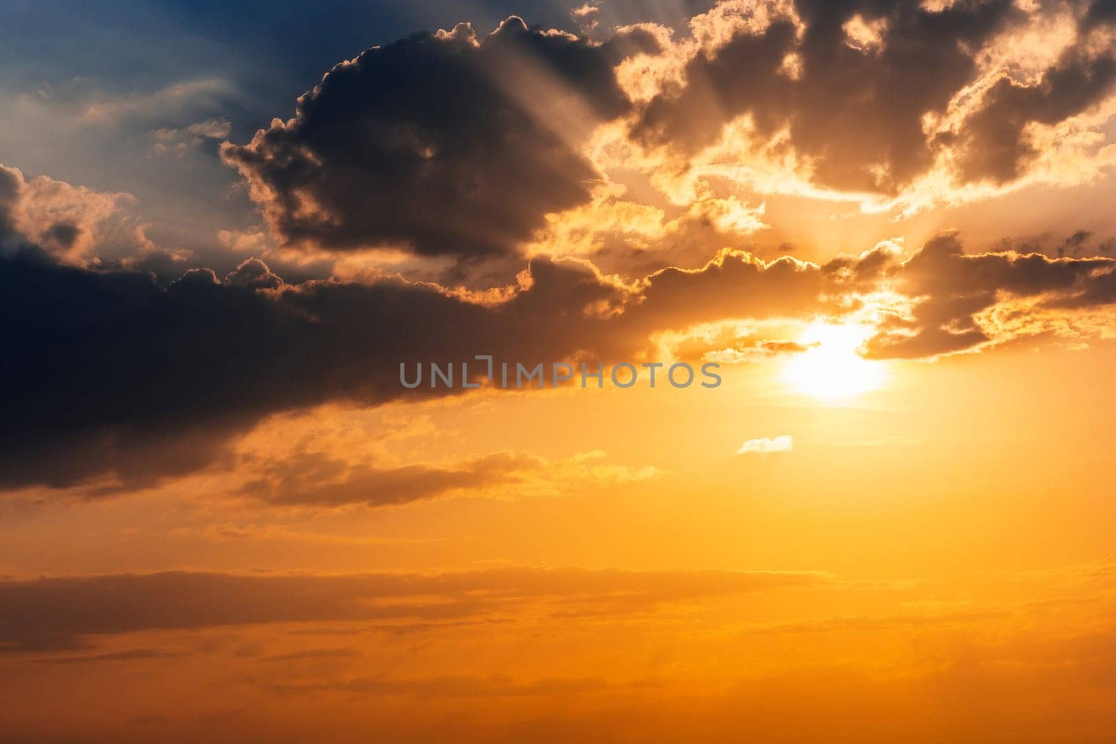 orange sunset with sunlight on cloudy sky. Background with sky with clouds in summer