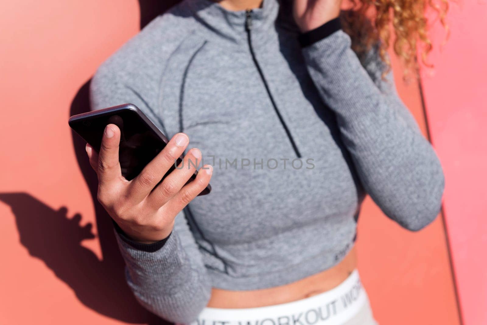 close up of the hand of an anonymous female athlete using cellphone, concept of technology of communication and modern lifestyle