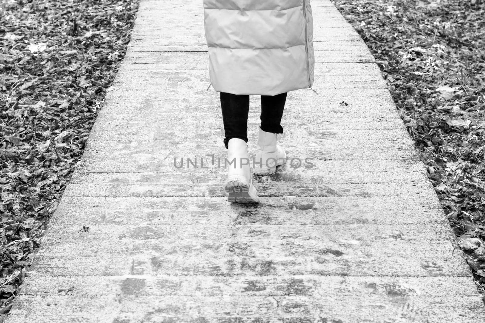 Woman walks on the wooden path walk in the park covered with frost
