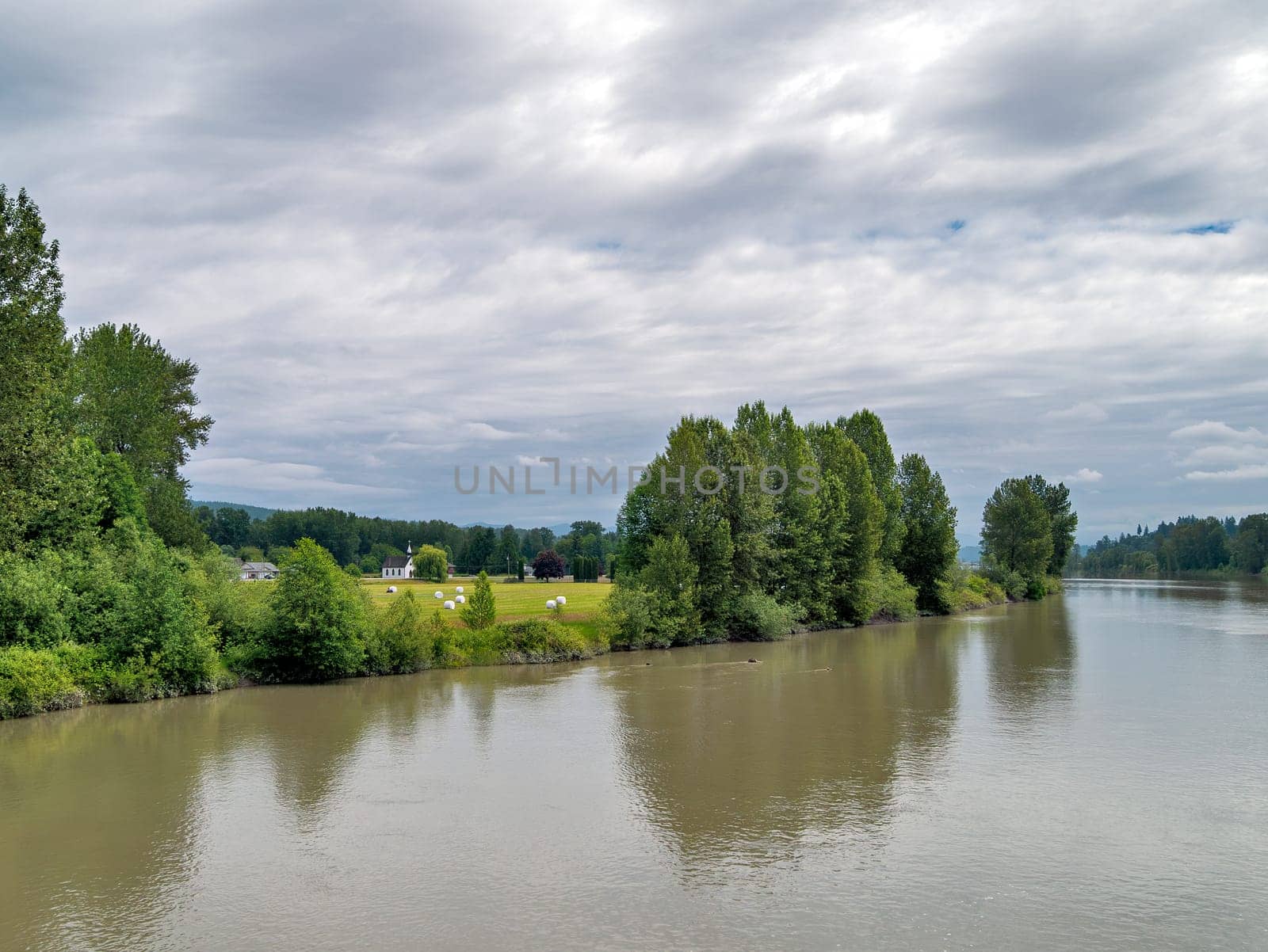 A beautiful river landscape with a white church on the shore.