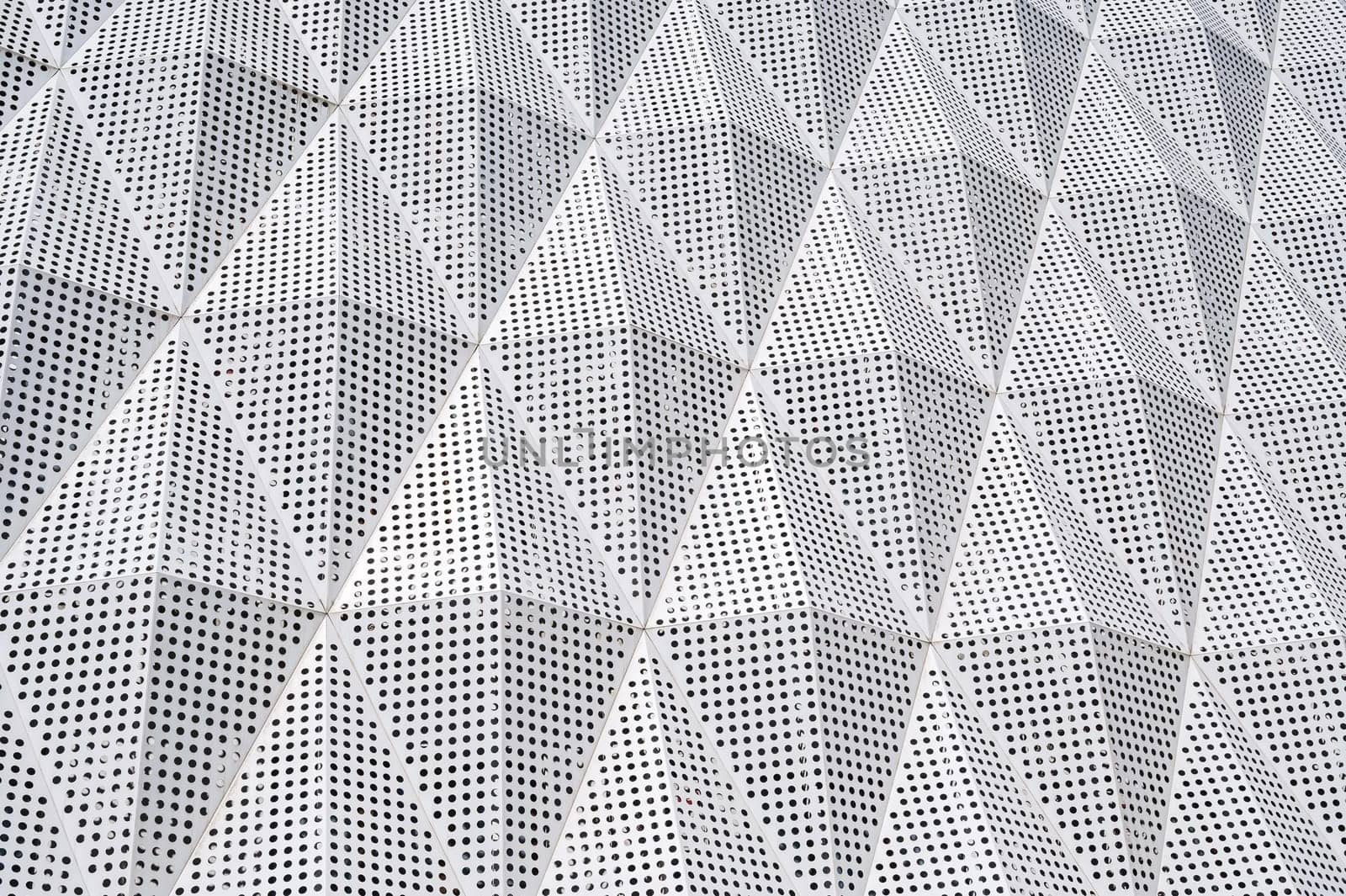 facade of a modern building is covered with geometric metal panels
