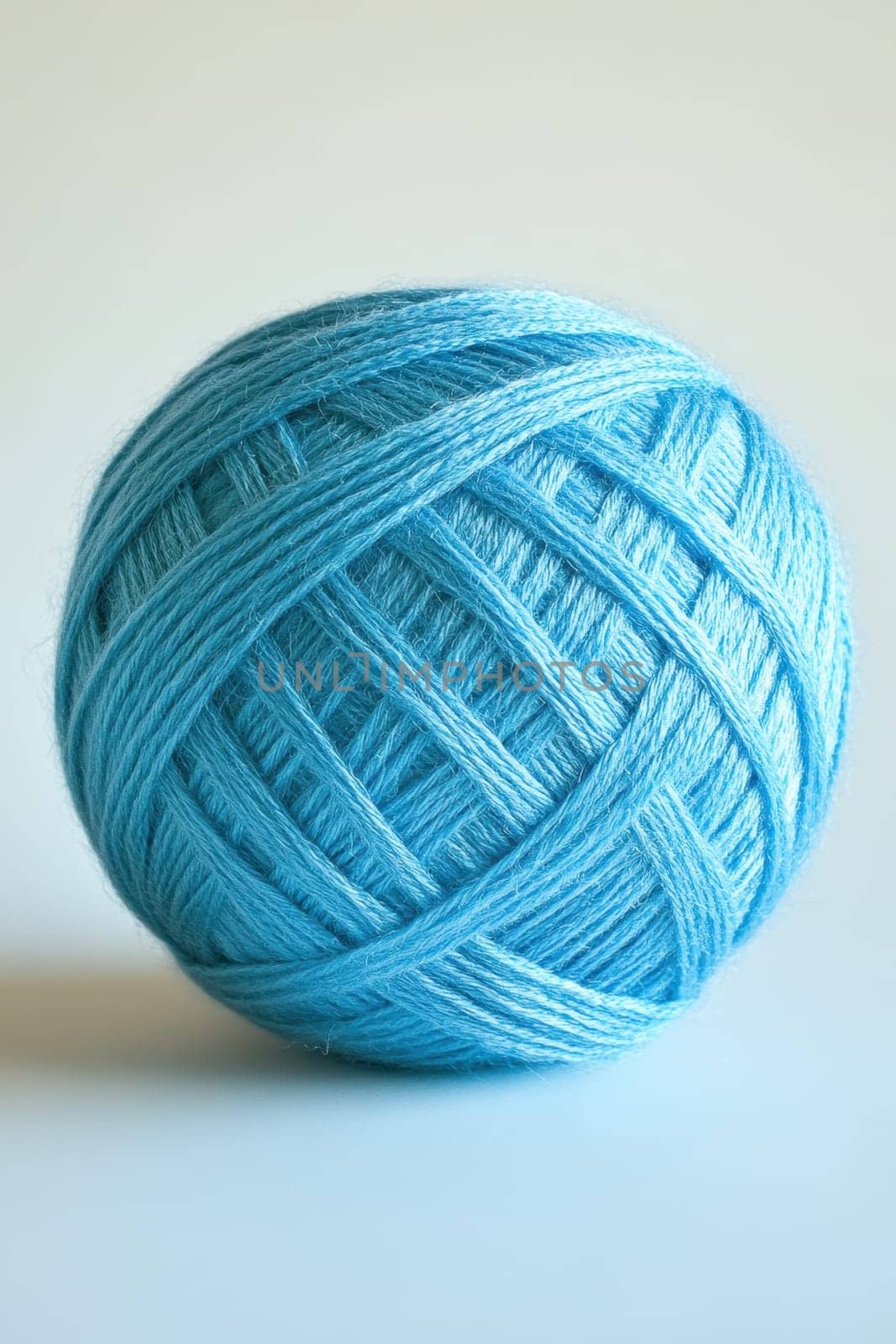 A blue ball of wool yarn standing out against a white background.