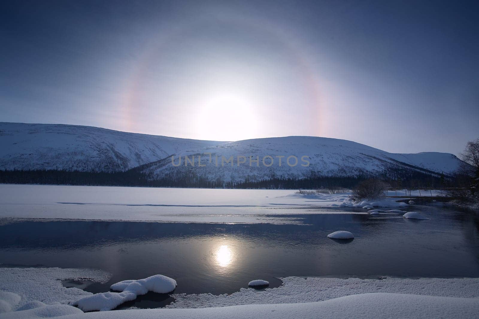 beautiful arctic snowy landscape with frozen lake, solar halo phenomenon,