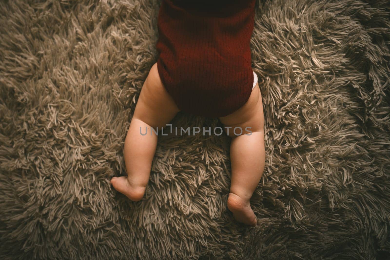 Adorable baby legs on fluffy brown bed coat. Babyhood and parenting concept. High quality photo