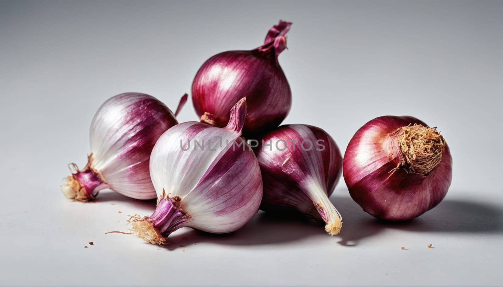 A collection of fresh red and white onions is arranged on a light surface, highlighting their glossy skin and unique shapes. The onions are visually appealing and ready for culinary use.