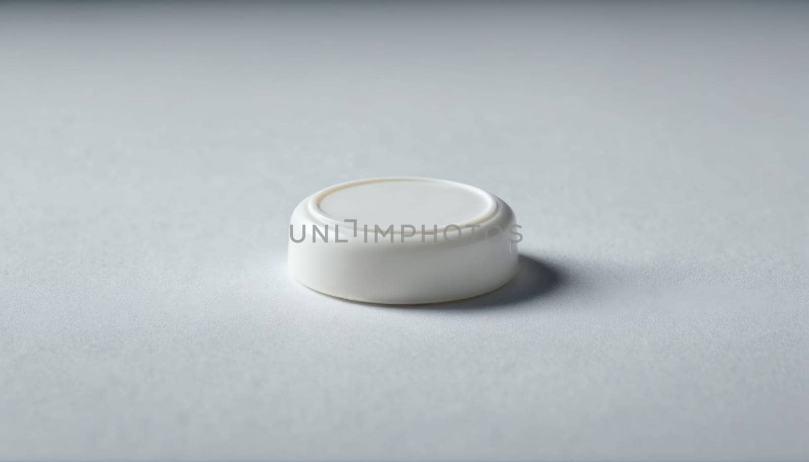 A round white object sits on a clean, smooth surface. Its minimalist design is highlighted by the soft shadow it casts, creating a modern, serene atmosphere.