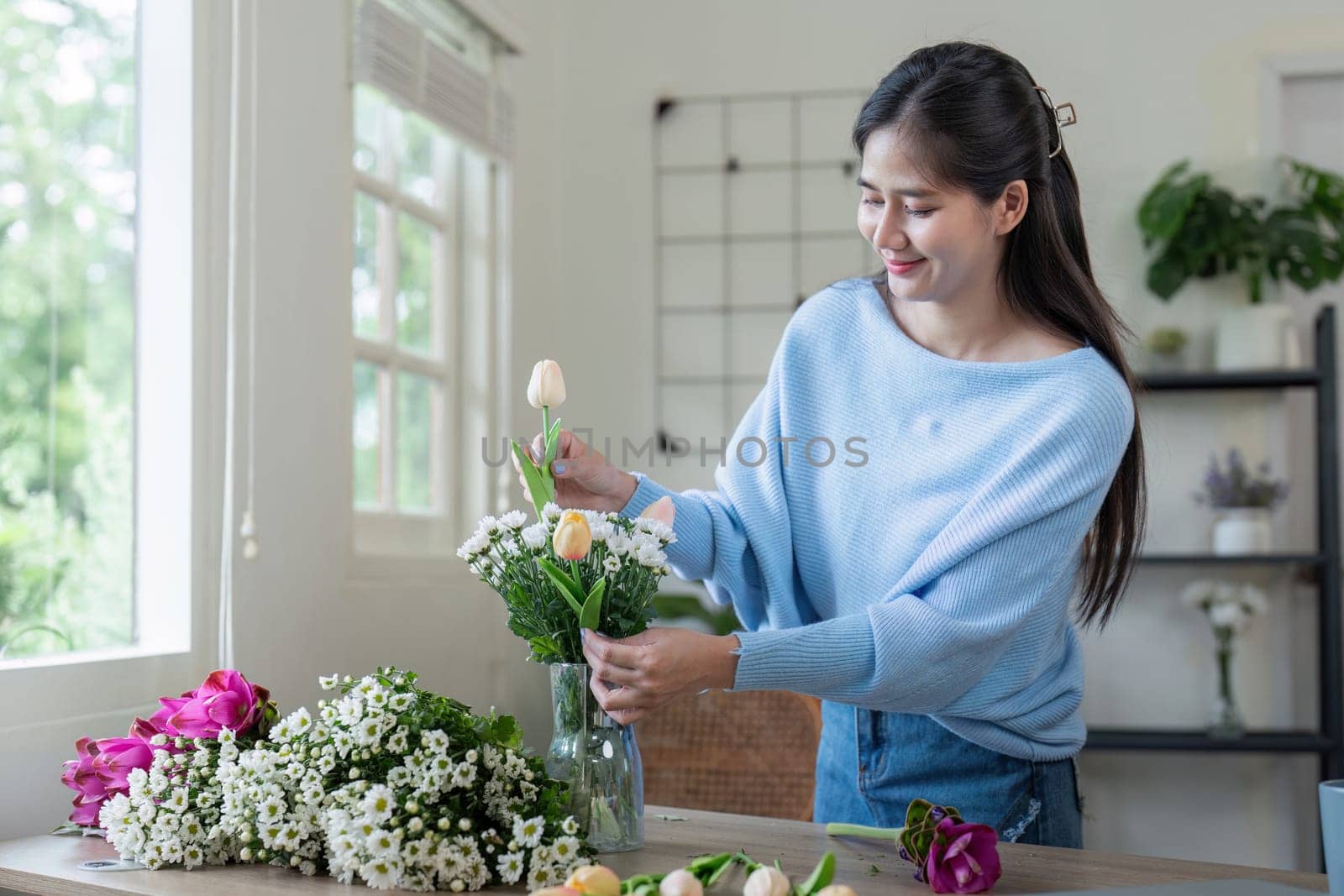 A woman enjoys arranging fresh flowers in a sunny room showcasing her creativity and love for floral design.
